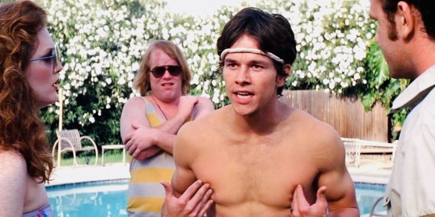 Dirk Diggler, played by Mark Wahlberg, standing in the middle of a conversation with the cast of Boogie Nights