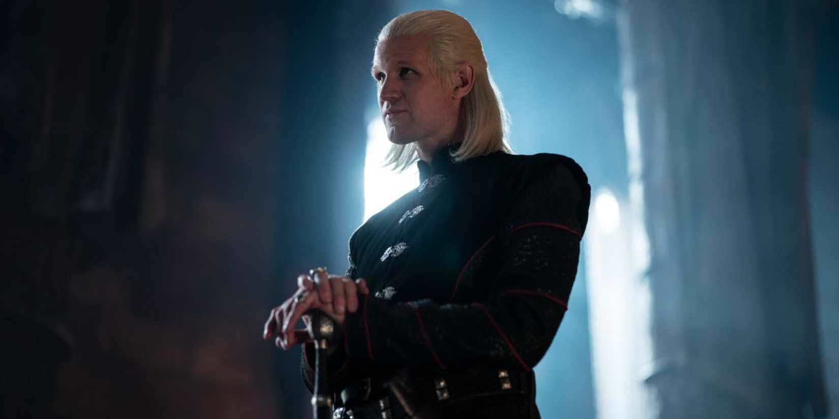 Daemon Targaryen resting his hands on his sword while standing and looking ahead in House of the Dragon