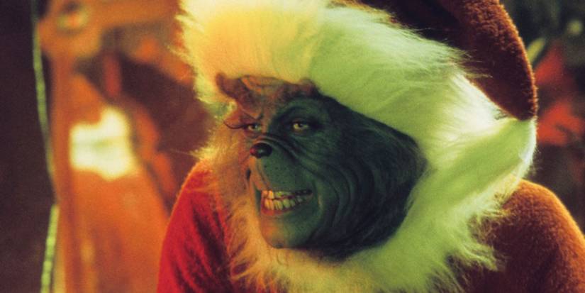Jim Carrey as the Grinch grinning and wearing a Santa costume in 'How the Grinch Stole Christmas'.