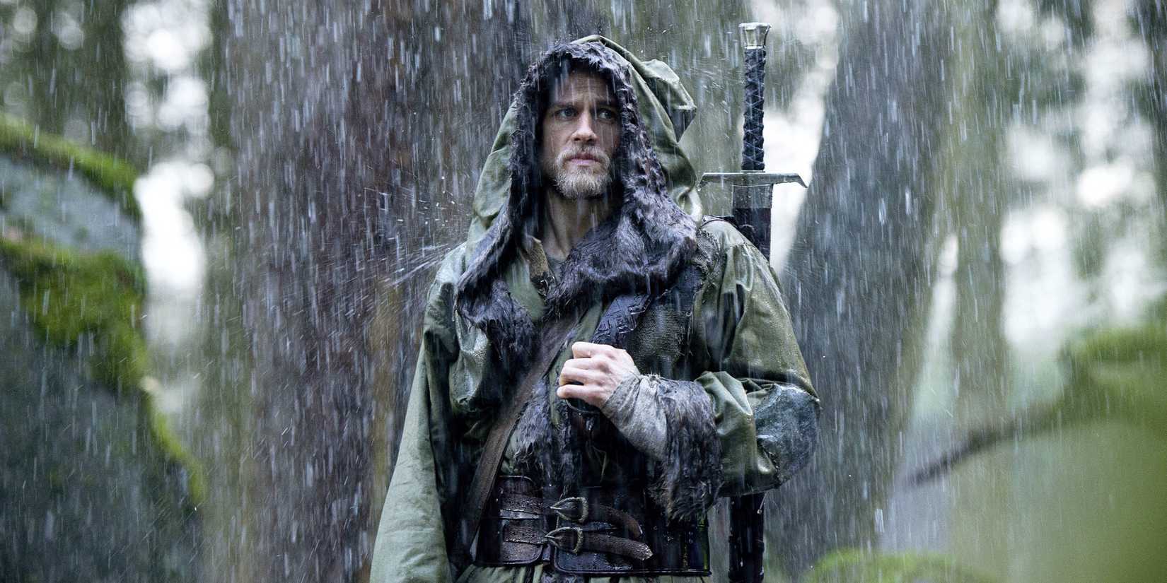 Charlie Hunnam as Arthur in the rain with Excalibur in 'King Arthur: Legend of the Sword'