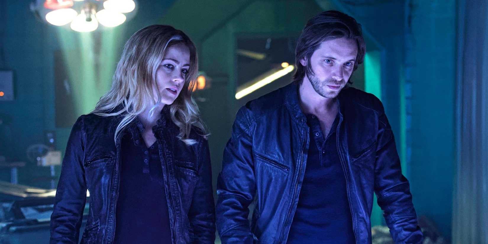 Amanda Schull as Cassandra and Aaron Stanford as James look at something with a blue glow in 12 Monkeys.