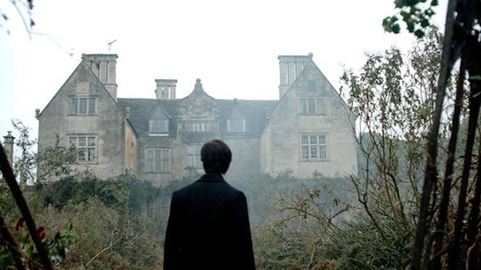 Arthur Kipps standing in front of Eel Marsh House in The Woman in Black.