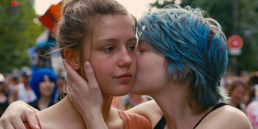 Adele and Emma kissing on the cheek outdoors with a crowd of people behind in Blue is the Warmest Color.