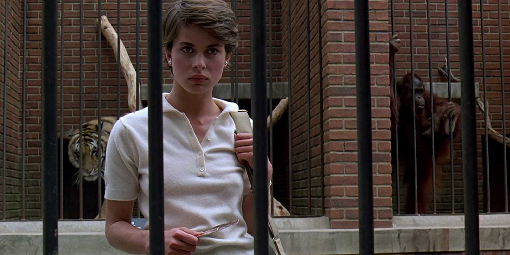 Irena standing behind bars at a zoo in Cat People