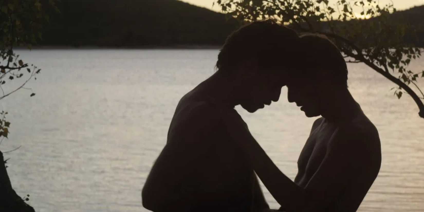 Two people against the sunset meeting their foreheads by a lake in Stranger by the Lake 