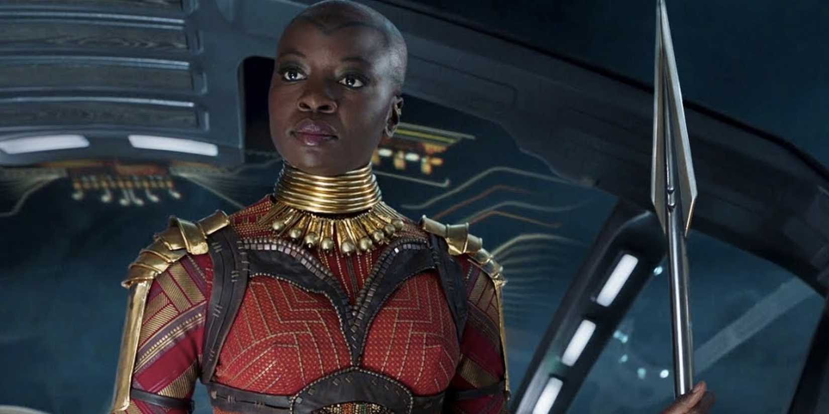 Danai Gurira kā okoye 'melnajā panterā', kas tur vibrāna šķēpu.