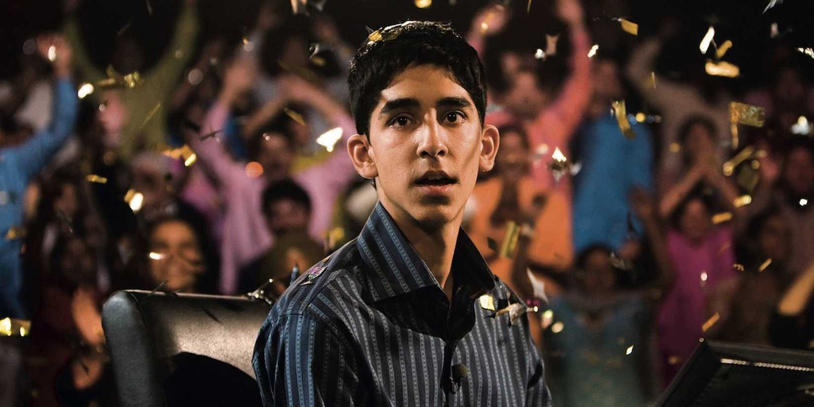 Dev Patel sebagai Jamal, tampak terkejut saat confetti berjatuhan di sekelilingnya di Slumdog Millionaire.