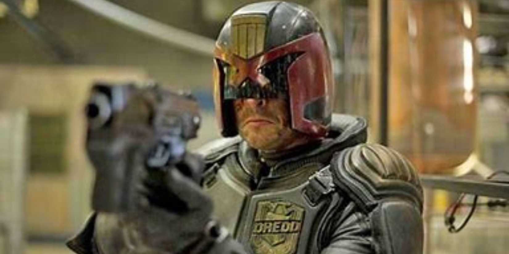 An armoured police officer in a dystopian future city aims his gun.