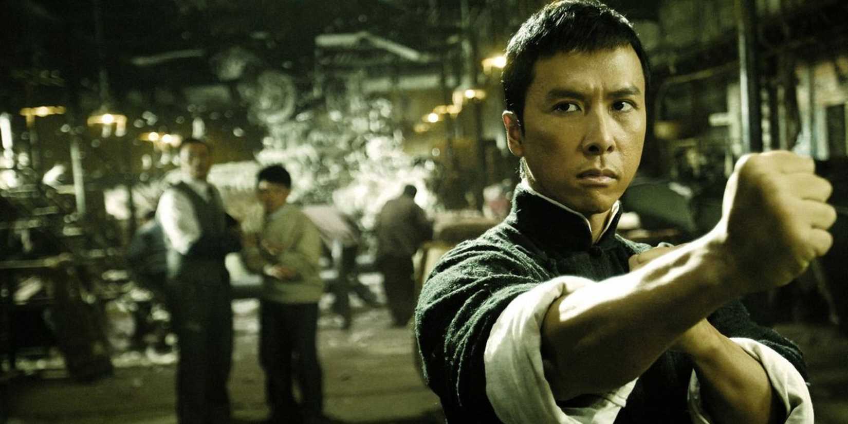 A man with a serious expression takes a martial arts stance with people looking on from behind in Ip Man.