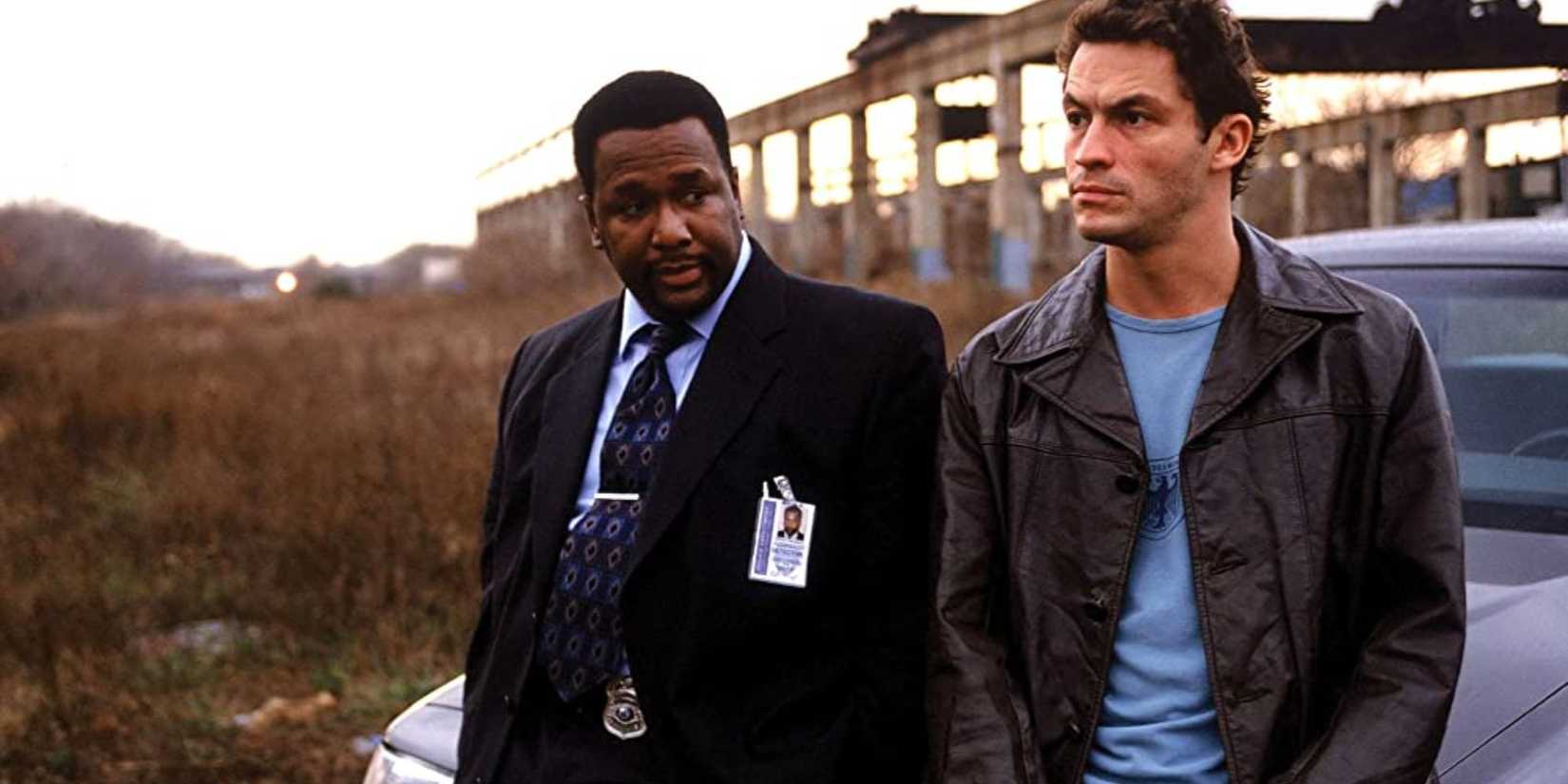 Wendell Pierce as Bunk Moreland and Dominic West as Jimmy McNulty sitting on the roof of a car in The Wire.