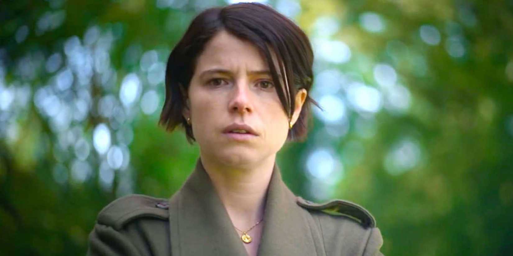 Jessie Buckley as Harper looking down in the woods in Men (2022)