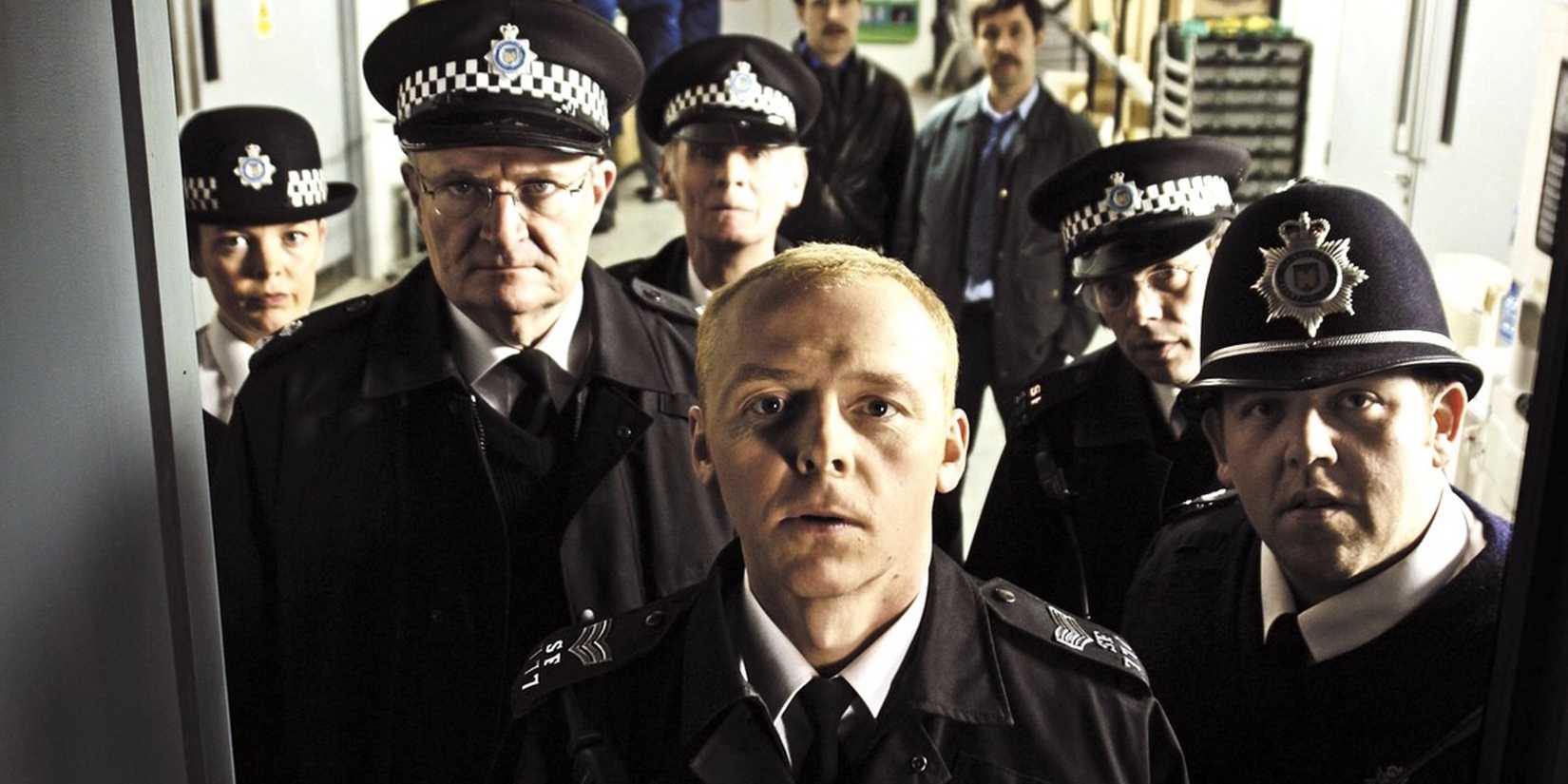 A group of police officers stand in a hallway in Hot Fuzz. Simon Pegg is at the front.