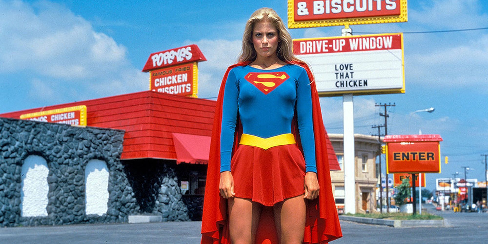 Supergirl standing in front of a Popeye's restaurant