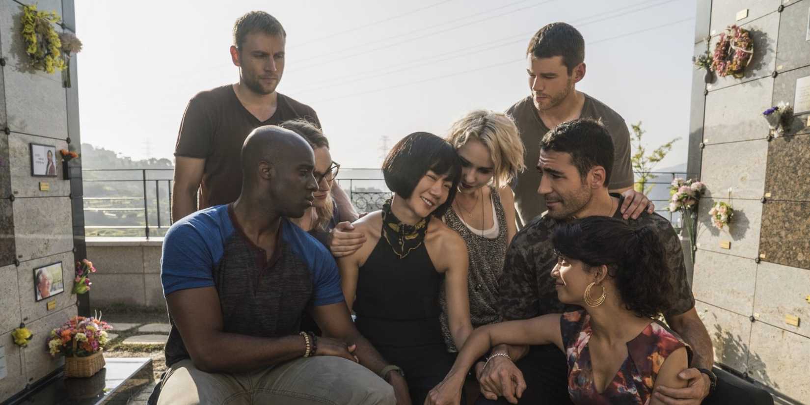The cast of Sense 8 huddle around Bae Doona on a rooftop balcony.