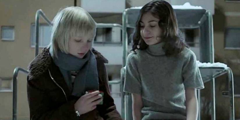 Two children sitting on a playset in the snow, looking at a Rubik's Cube in Let the Right One in