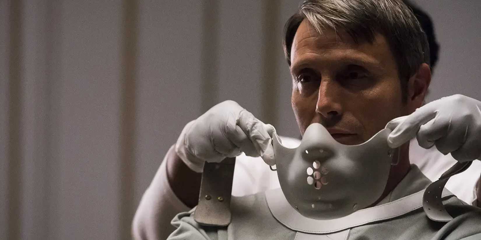 hands putting on a white mask on a tied man