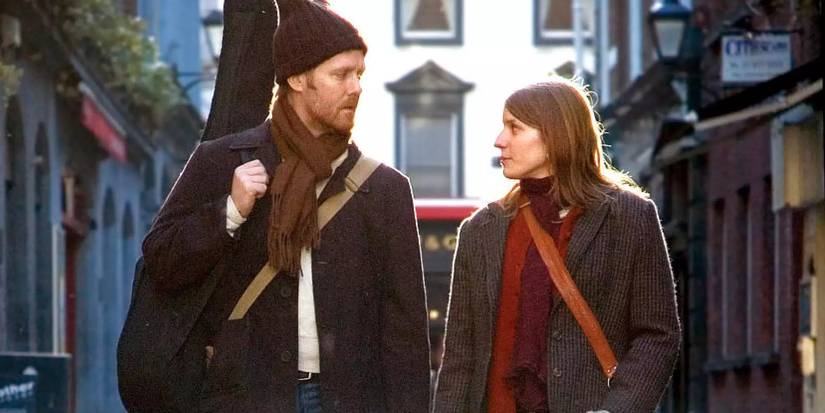 A man and a woman looking at each other while walking down the street in Once (2007) (1)