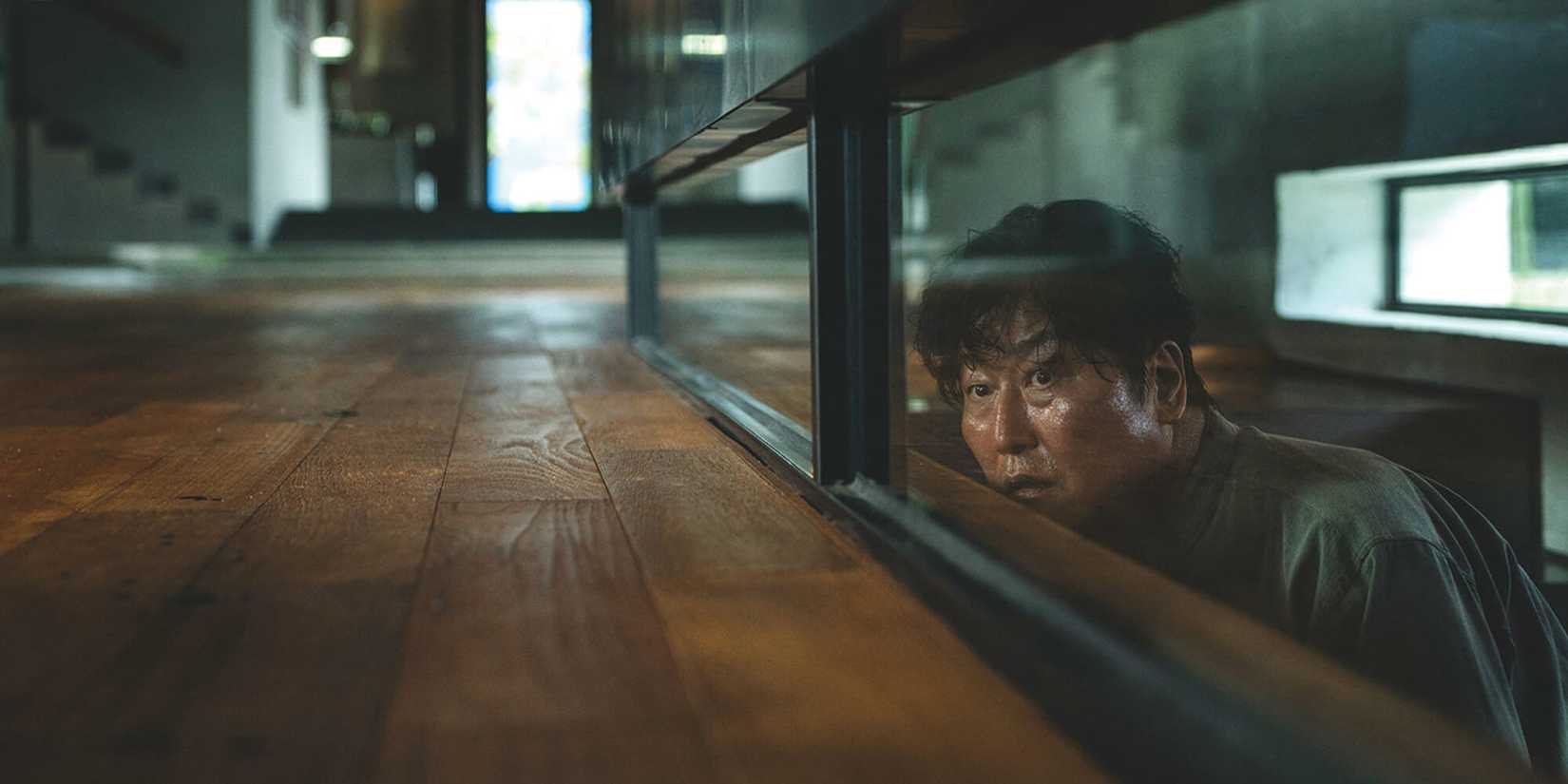 Song Kang-ho as Kim Ki-taek, coming up the basement stares and peering through a glass wall in Parasite