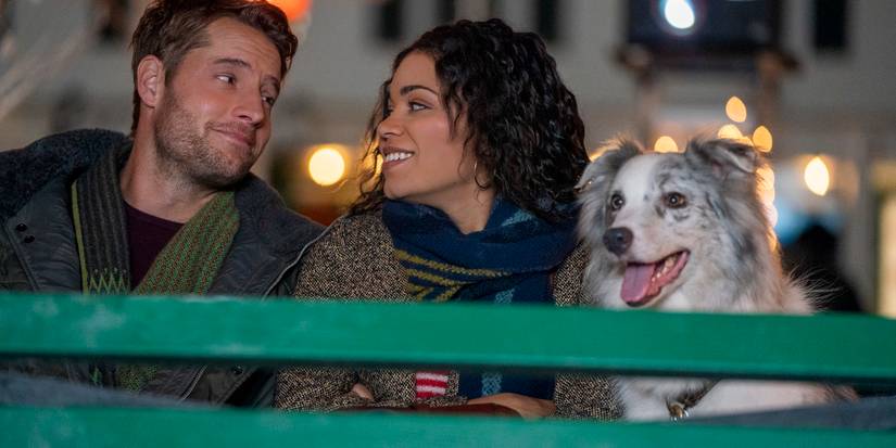 Justin Hartley and Barrett Doss as Jake and Rachel in The Noel Diary smiling in a carriage with their dog.