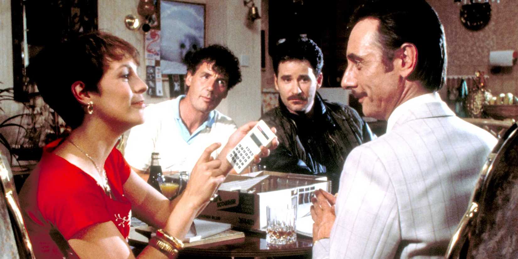 Jamie Lee Curtis, Kevin Kline, Michael Palin, and Tom Georgeson in A Fish Called Wanda sitting at the table and having a conversation.