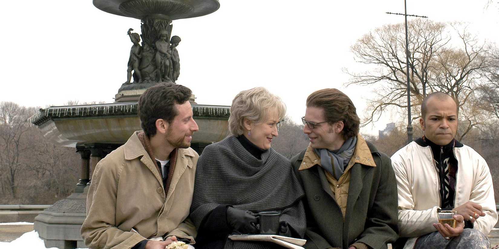 Three men talking to a woman in front of a fountain in "Angels in America" on HBO.