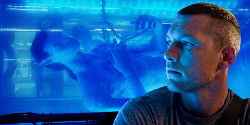 Sam Worthington looking to his right with an avatar in a water tank behind him in Avatar
