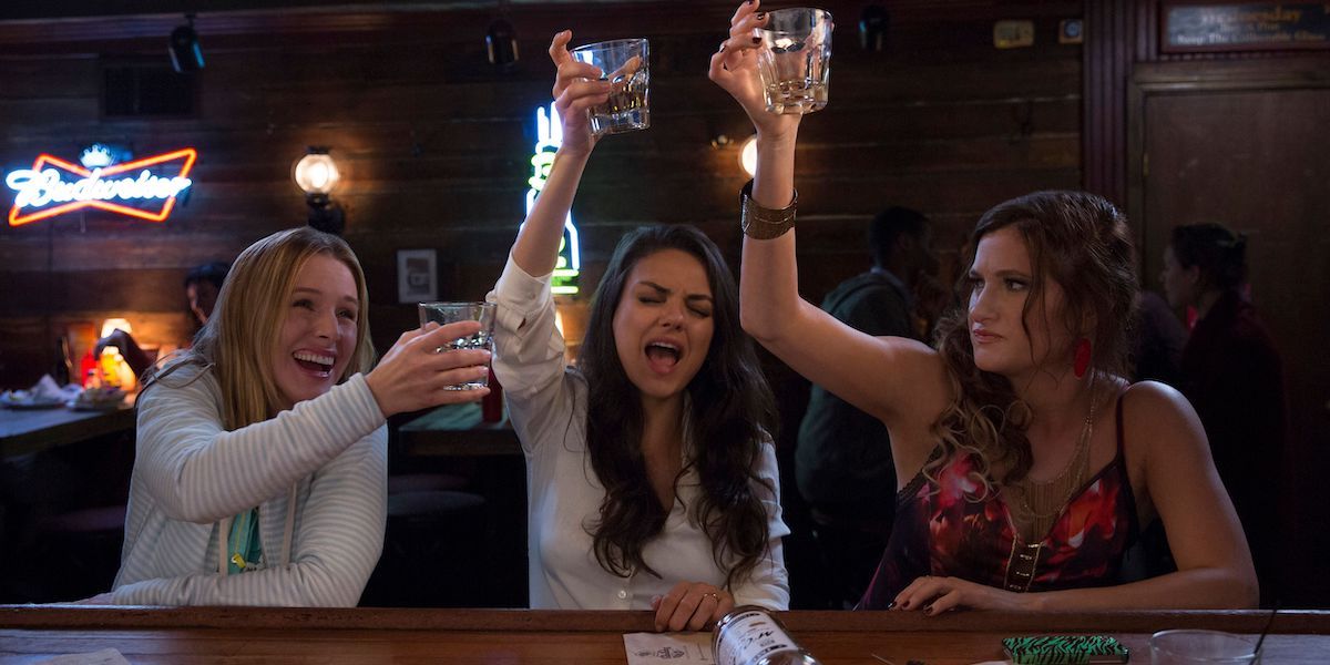 Kristen Bell as Kiki, Mila Kunis as Amy, and Kathryn Hahn as Carla toasting in a bar in Bad Moms.