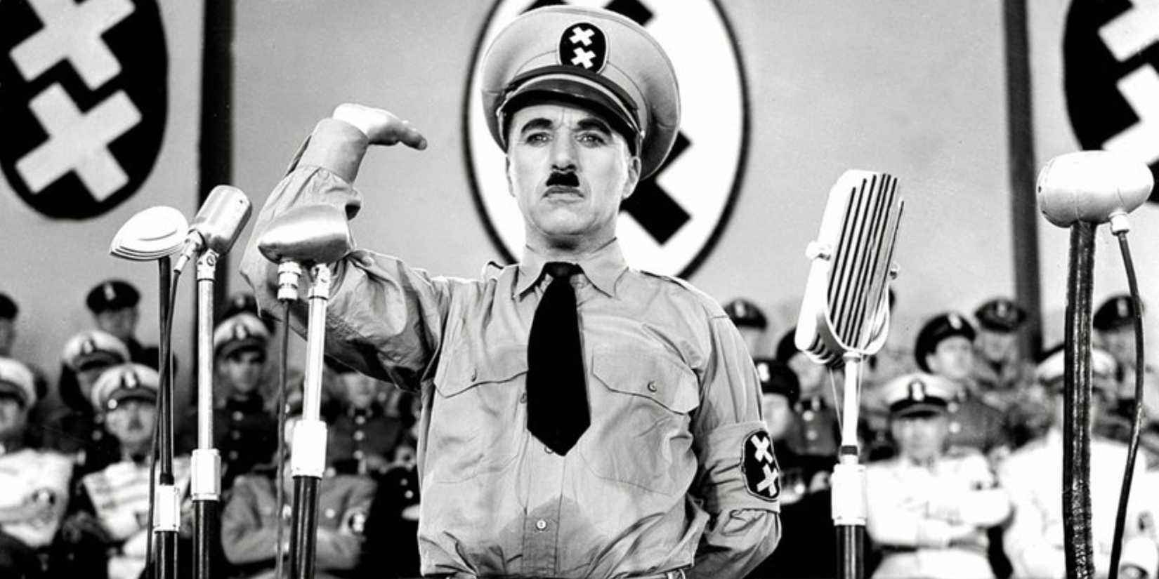 Charlie Chaplin dressed as Adolf Hitler raising his arm and standing on a podium in The Great Dictator