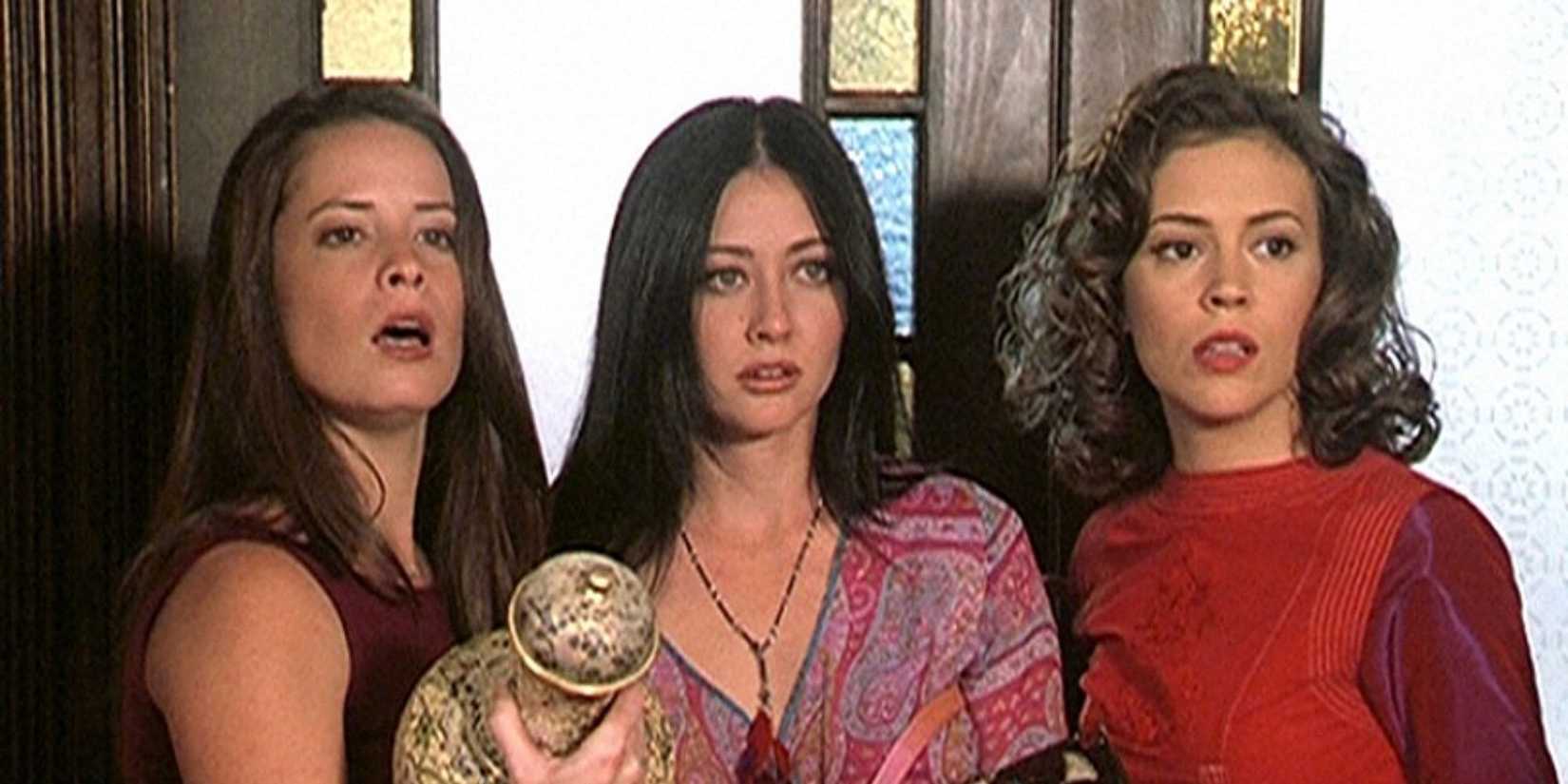 Holly Marie Combs, Shannon Doherty and Alyssa Milano stand in front of a door with stained-glass in Charmed