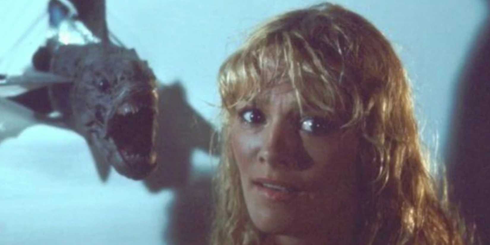 Loretta with a piranha flying toward her head with its mouth wide open in Piranha II: The Spawning