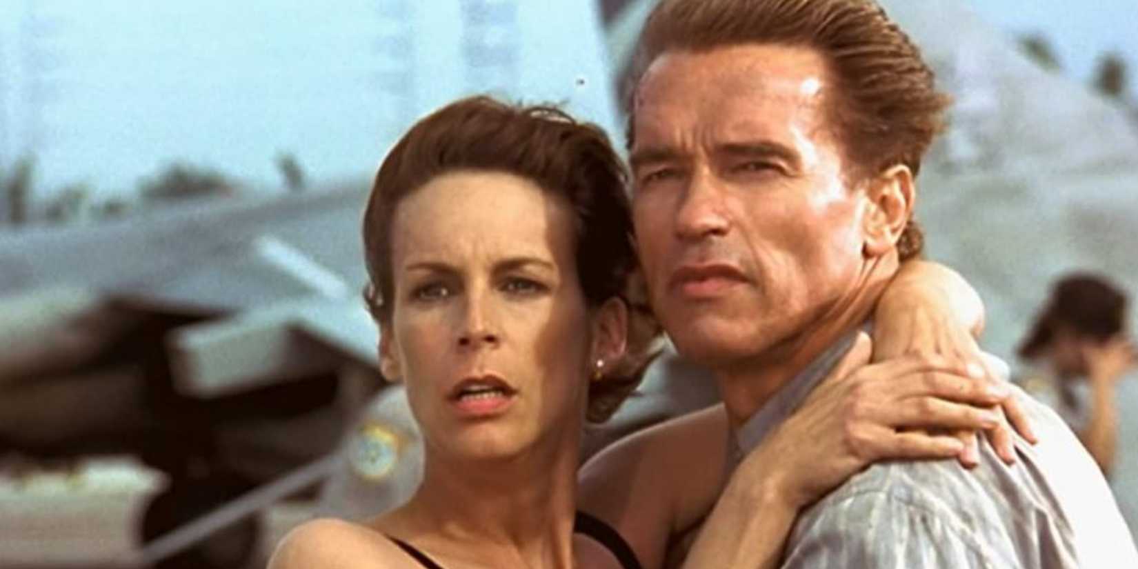 Jamie Lee Curtis and Arnold Schwarzenegger as Helen and Harry Tasker, holding each other in True Lies