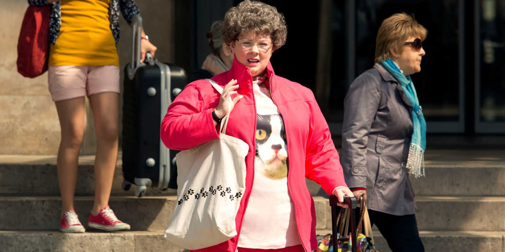 Susan dressed in an ugly outfit standing on a sidewalk looking to the distance in Spy.