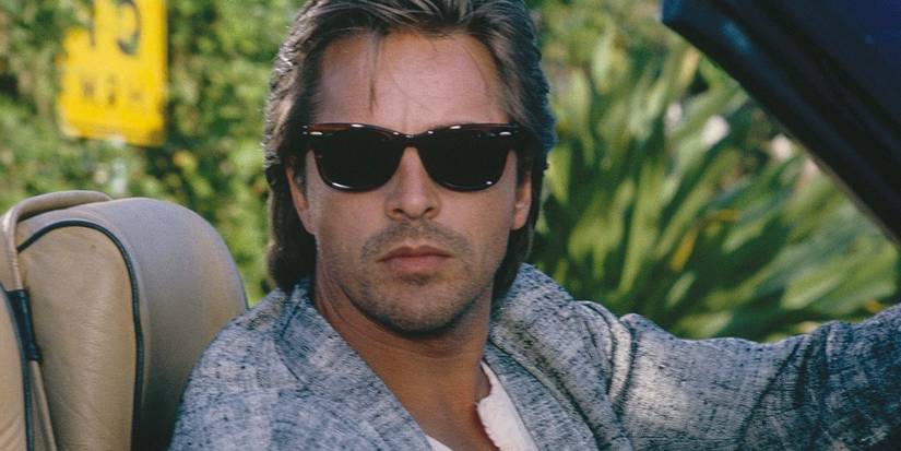 دون جونسون بدور جيمس كروكيت يرتدي نظارة شمسية ويحدق خارج سيارته في فيلم "Miami Vice".