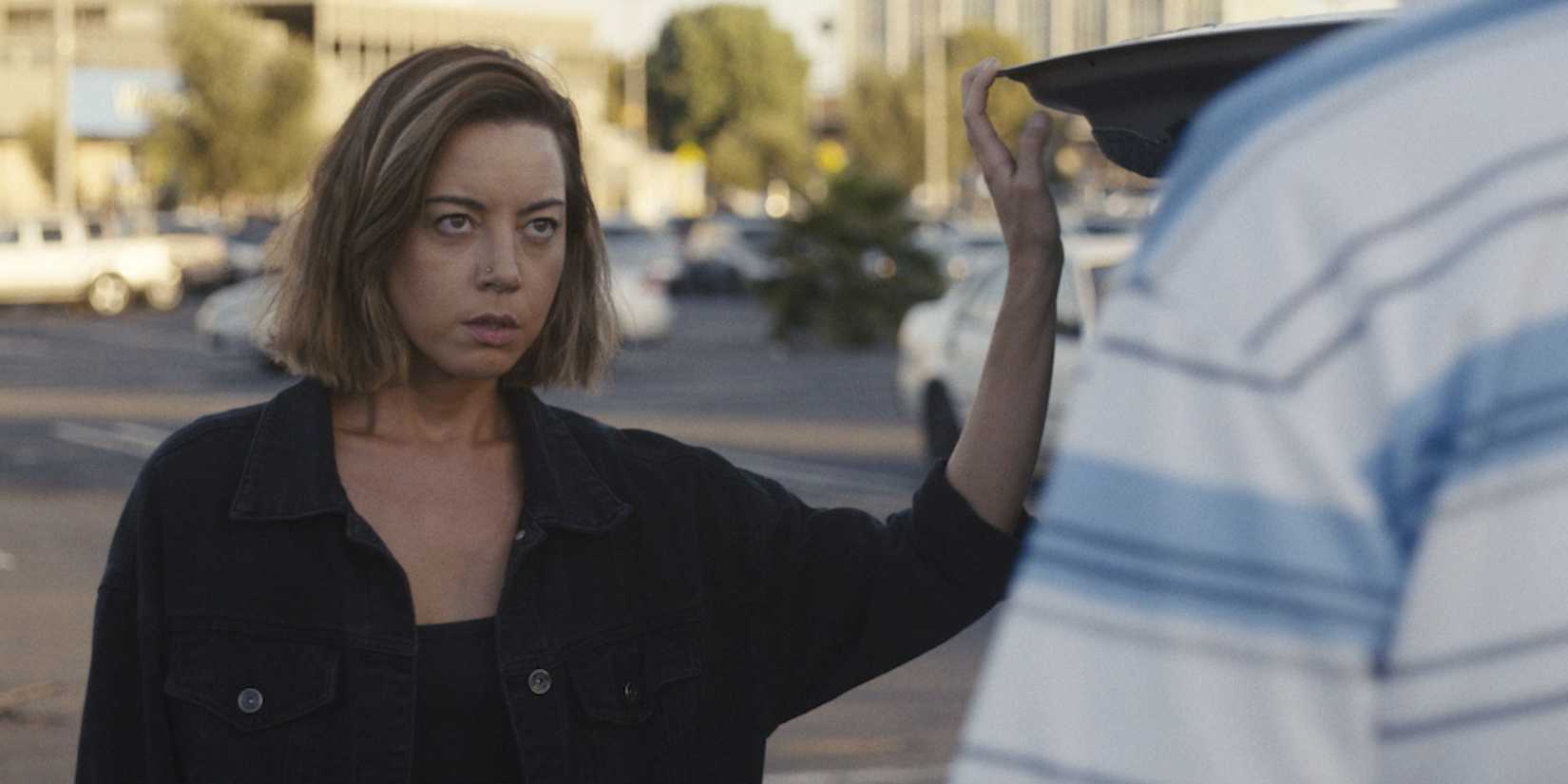 Aubrey Plaza as Emily in Emily the Criminal holding open the boot of her car during a confrontation