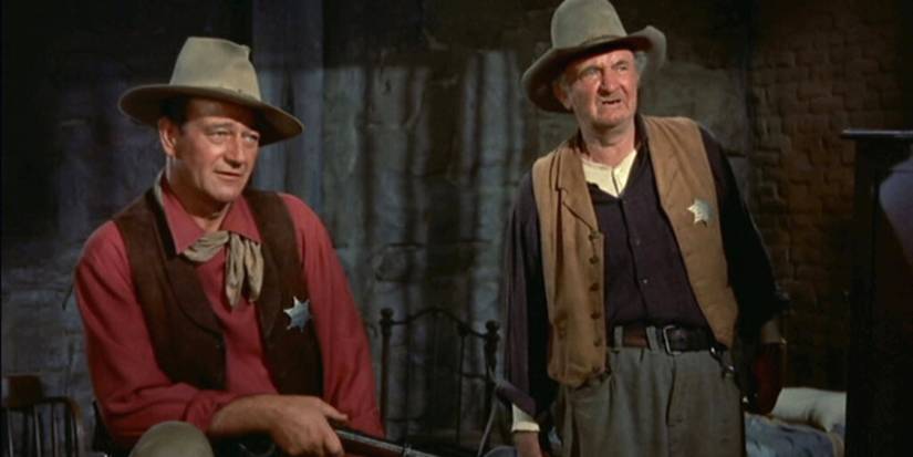 John Wayne sitting and Walter Brennan standing next to him in Rio Bravo