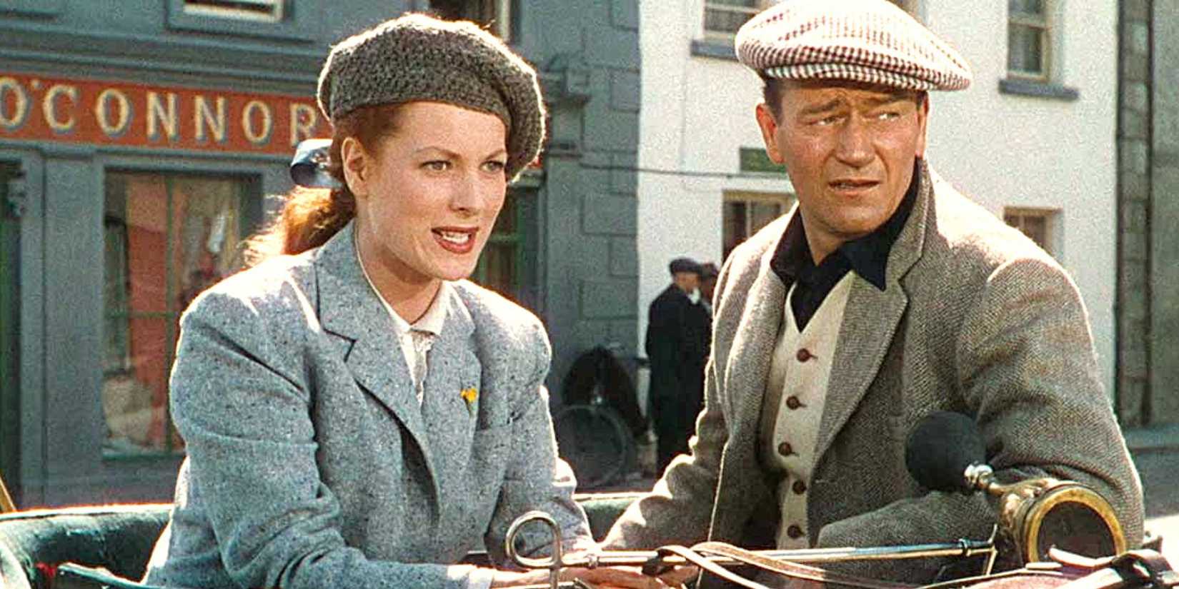 Maureen O'Hara and John Wayne sitting in a carriage looking forward in The Quiet Man