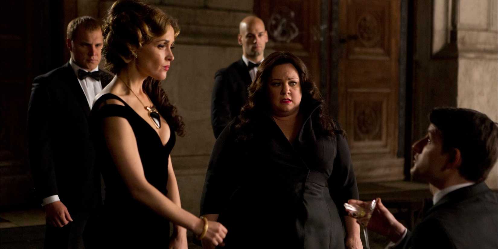 Rose Byrne and Melissa McCarthy as Raina and Susan surrounded by men in Spy