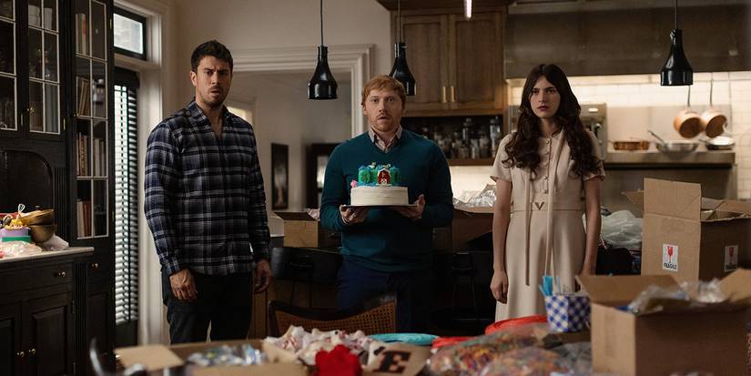 Rupert Grint and Nell Tiger Free with another person with a cake and decorations look shocked in Servant.