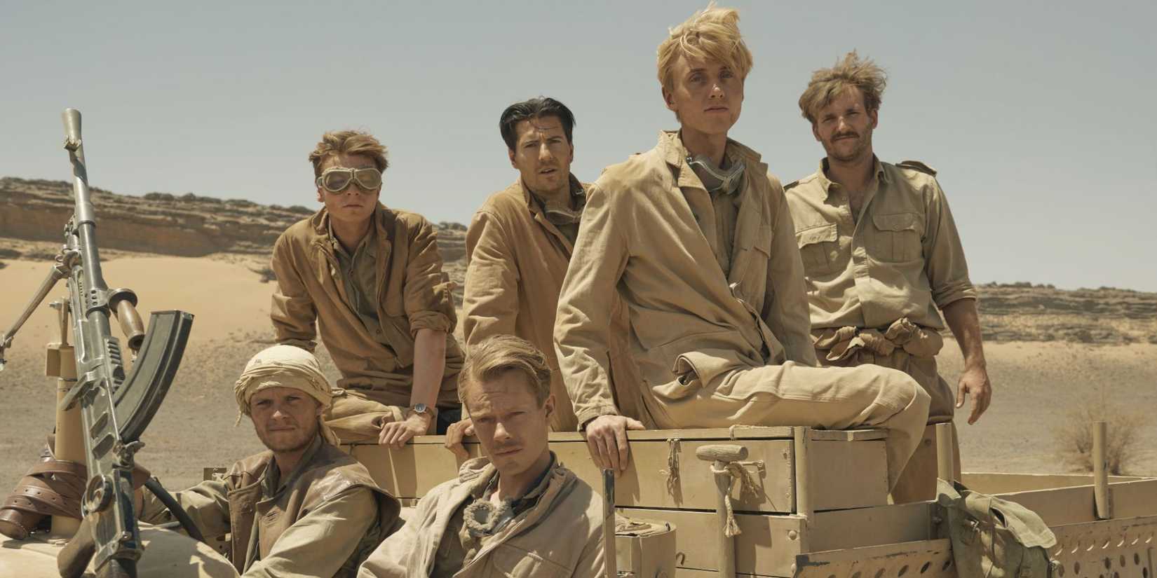 Soldiers sit in a vehicle in khaki desert fatigues in SAS Rogue Heroes.