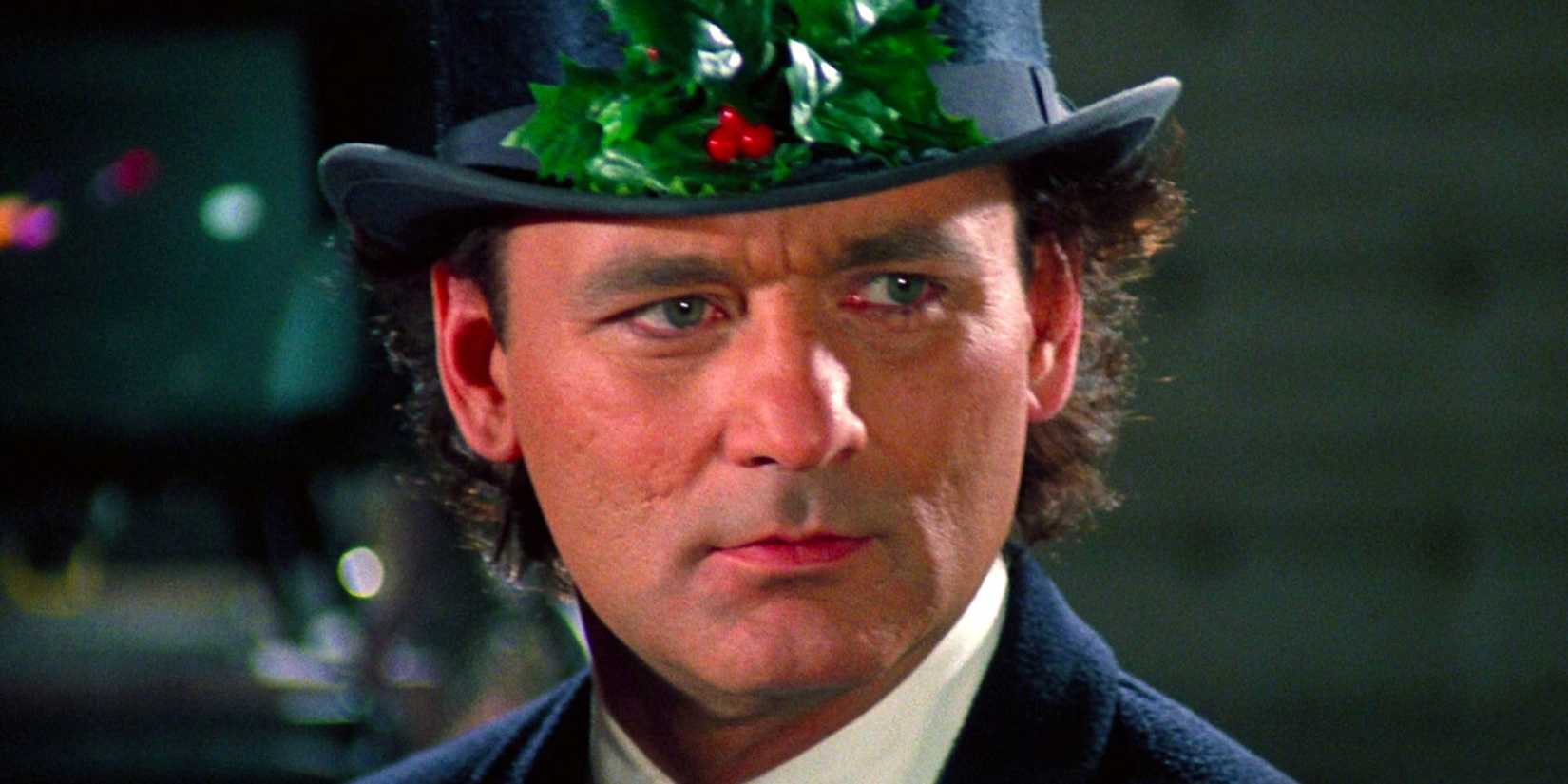 Bill Murray as Frank Cross wears a top hat with a holly on it in Scrooged.