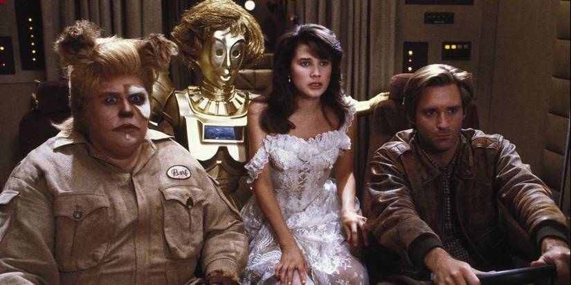 Barf (John Candy), Dot Matrix (Lorene Yarnell Jansson), Princess Vespa (Daphne Zuniga), and Lone Starr (Bill Pullman) looking concerned in Spaceballs.