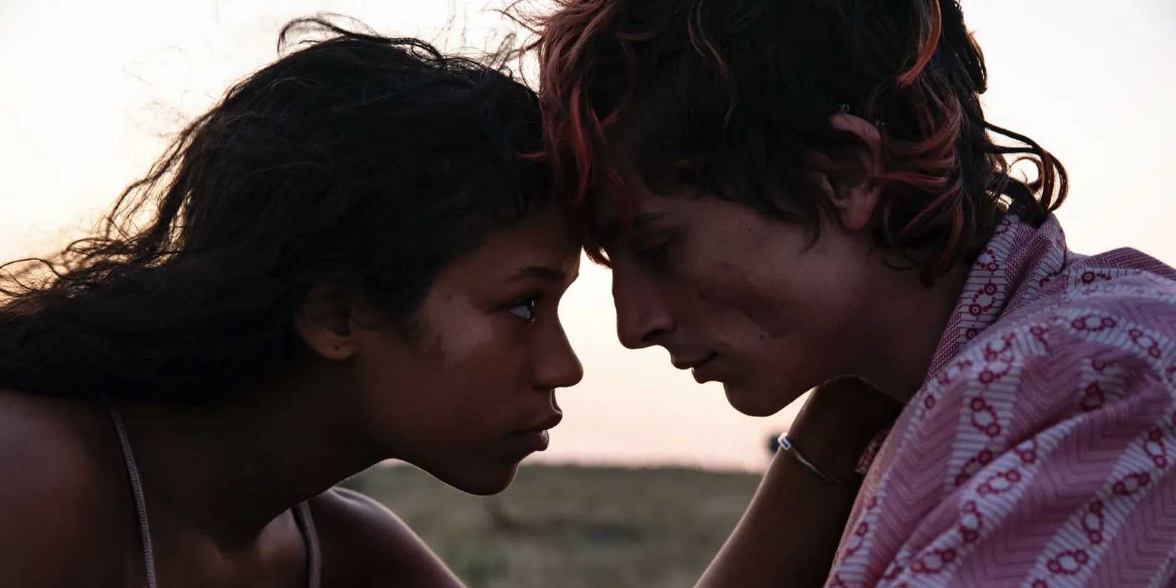 Taylor Russell and Timothée Chalamet touch foreheads and intently look at each other in Bones and All.