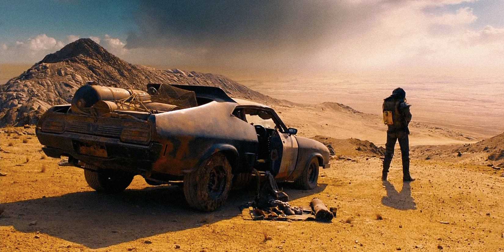 A figure with his back to the camera next to a car in a desert in Mad Max: Fury Road