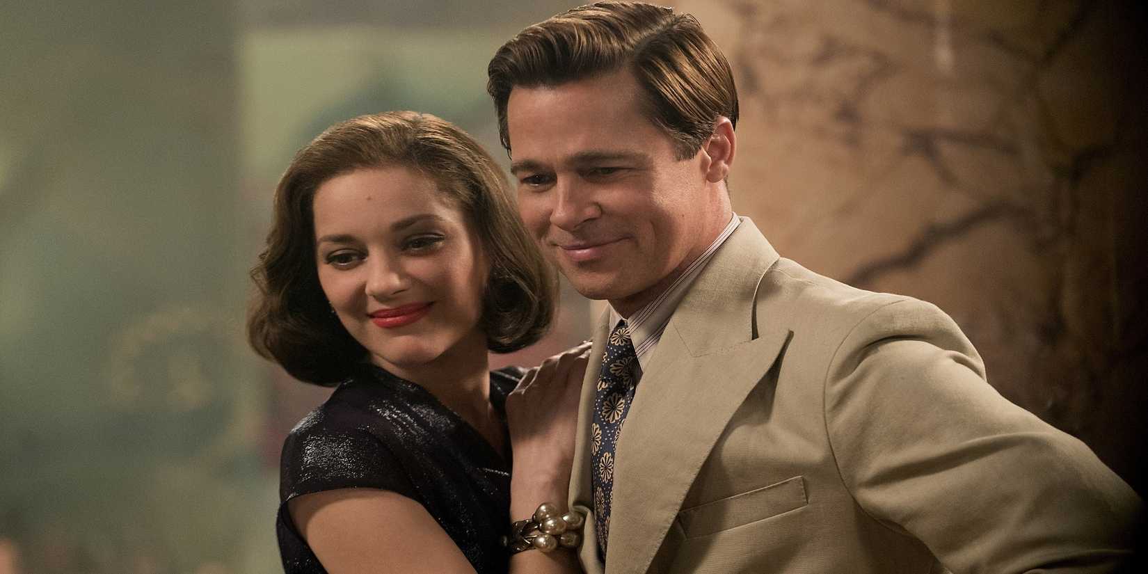 Max and Marianne, played by actors Brad Pitt and Marion Cotillard, stand together smiling down at someone in Allied.