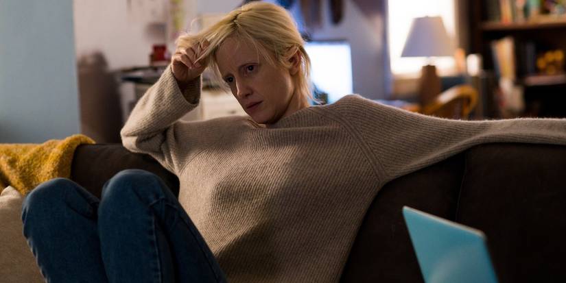 Andrea Riseborough as Tasya Vos sits on a couch and looks stressed in Possessor.