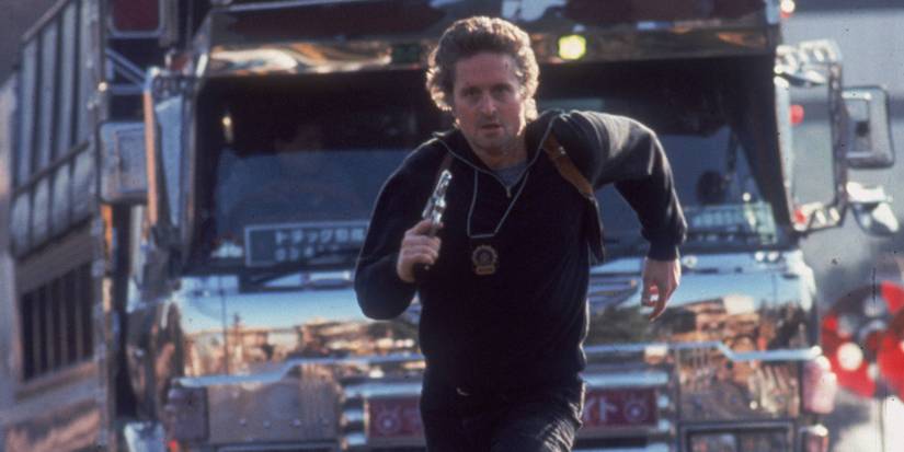 Michael Douglas as Nick Concklin running in front of a large truck while holding a gun in Black Rain.