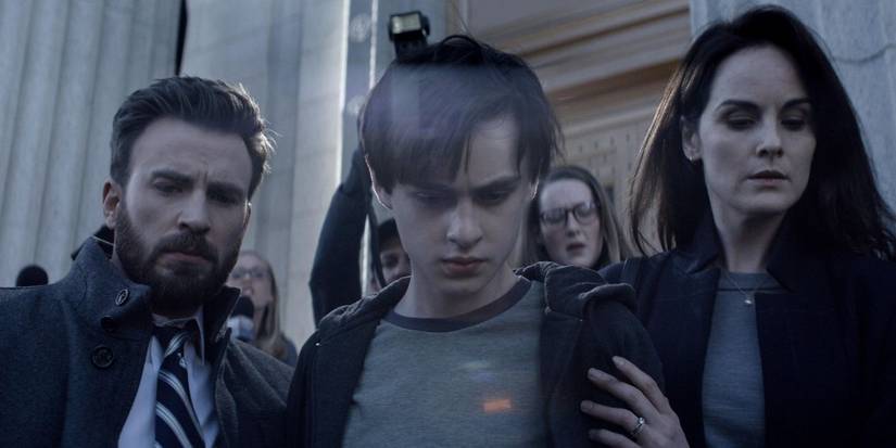 Andy (Chris Evans) & Laurie (Michelle Dockery) walk Jacob (Jaeden Martell) past press in Defending Jacob.
