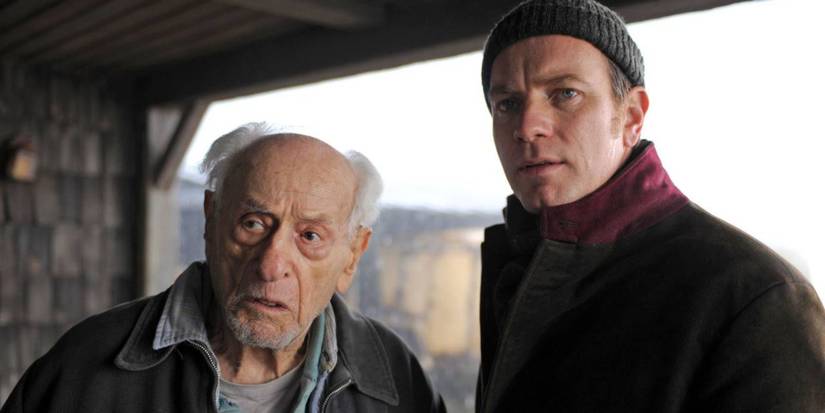 An old man and the Ghost stare towards the camera