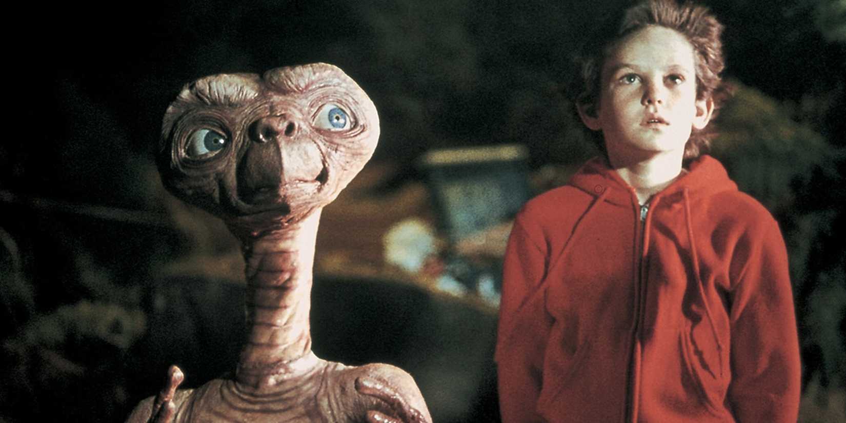 Henry Thomas sebagai Elliot berdiri di samping ET dalam 'ET the Extra-Terrestrial' (1982)