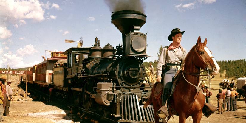 Richard Widmark as Mike King riding a horse in front of a train in How the West Was Won (1962)